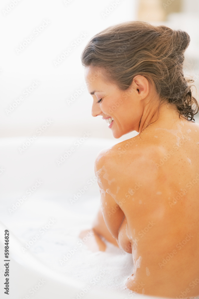 Happy young woman sitting in bathtub. rear view Happy young woman sitting in bathtub. rear view