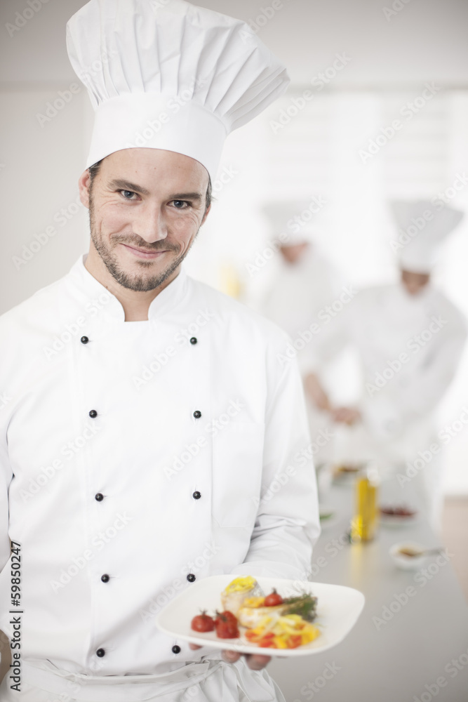 chef presenting a dish with his team in background chef presenting a dish with his team in background