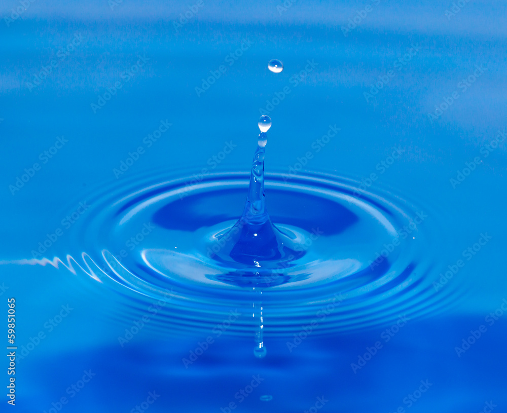 a drop of water falling in blue water