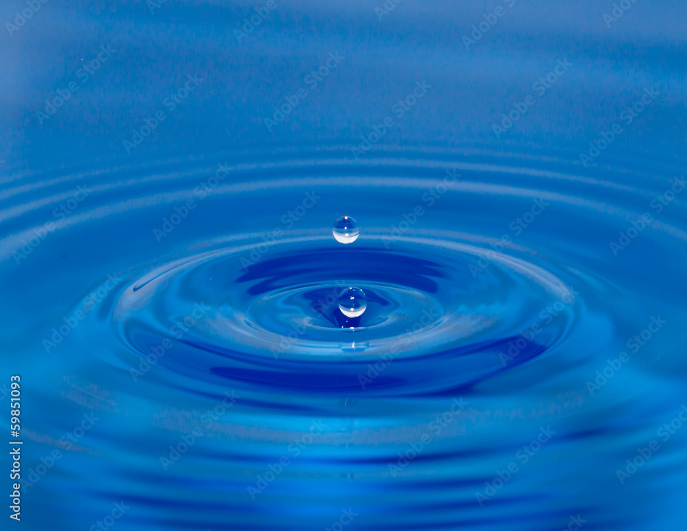 a drop of water falling in blue water a drop of water falling in blue water