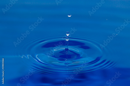 a drop of water falling in blue water
