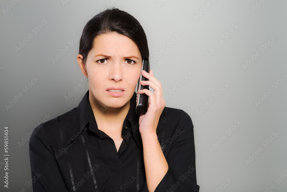 Verwirrte Frau telefoniert mit ihrem Mobiltelefon Verwirrte Frau telefoniert mit ihrem Mobiltelefon