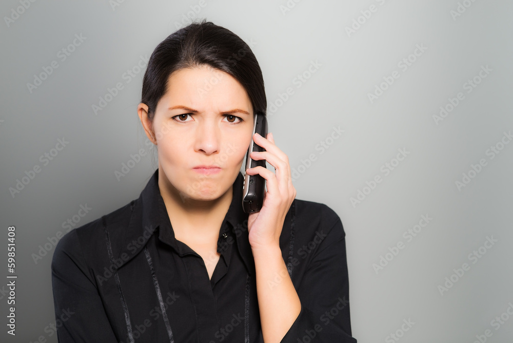 Verwirrte Frau telefoniert mit ihrem Mobiltelefon Verwirrte Frau telefoniert mit ihrem Mobiltelefon