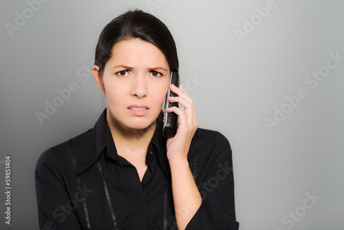 Verwirrte Frau telefoniert mit ihrem Mobiltelefon