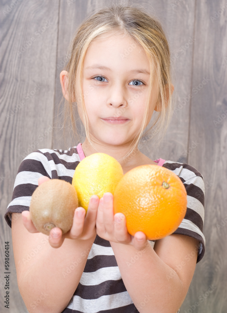 little girl holding kiwi, lemon and orange little girl holding kiwi, lemon and orange