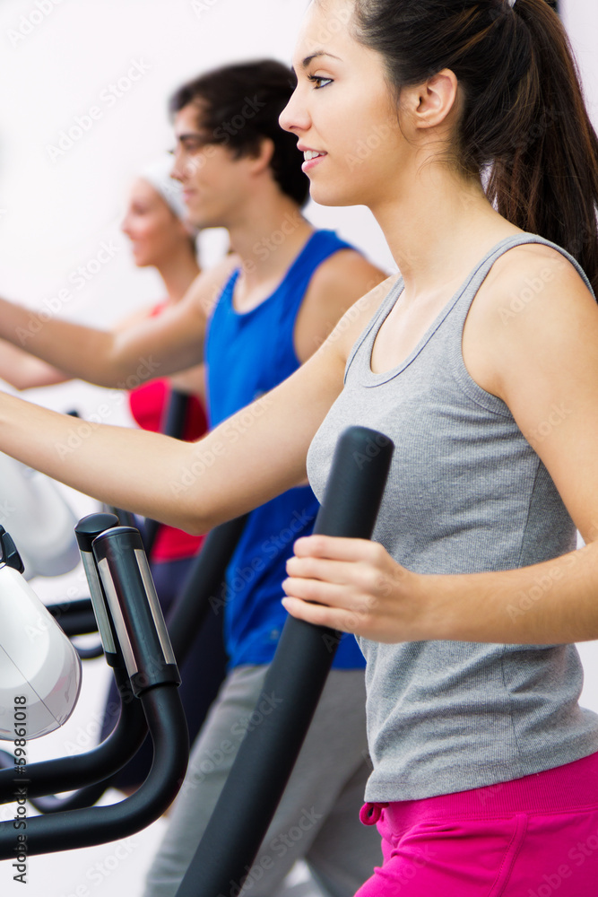 Young people with elliptic machine in the gym Young people with elliptic machine in the gym