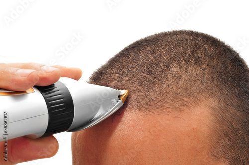 man cutting his hair with an electric hair clipper photo