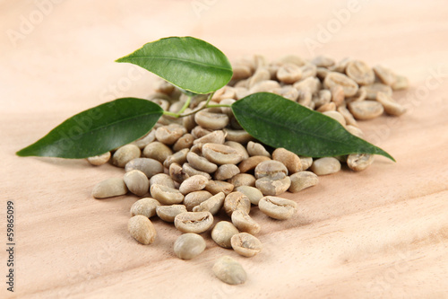Green coffee beans and leaves on wooden background