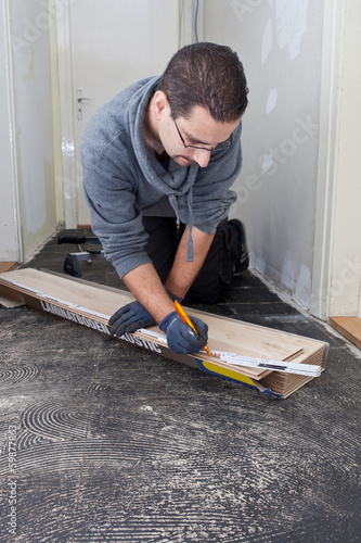 Carpenter measuring new wooden floor boards