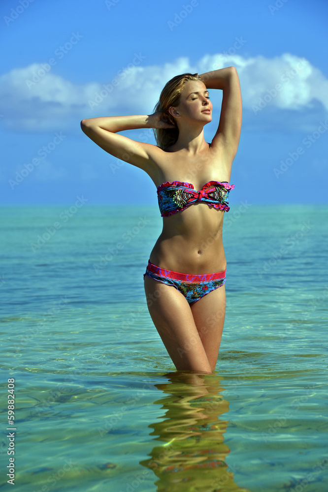 Bikini model posing sexy at tropical beach location