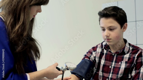 Nurse measuring blood pressure of teenager boy during visit