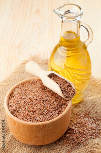 mortar of flax seeds with wooden scoop and linseed oil in glass
