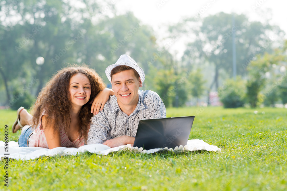 couple lying together in a park with laptop couple lying together in a park with laptop