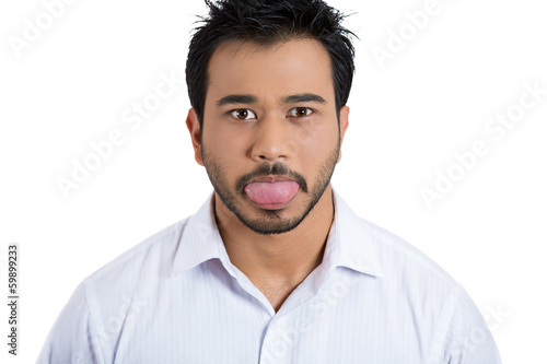 Funny, unhappy young man sticking out his tongue