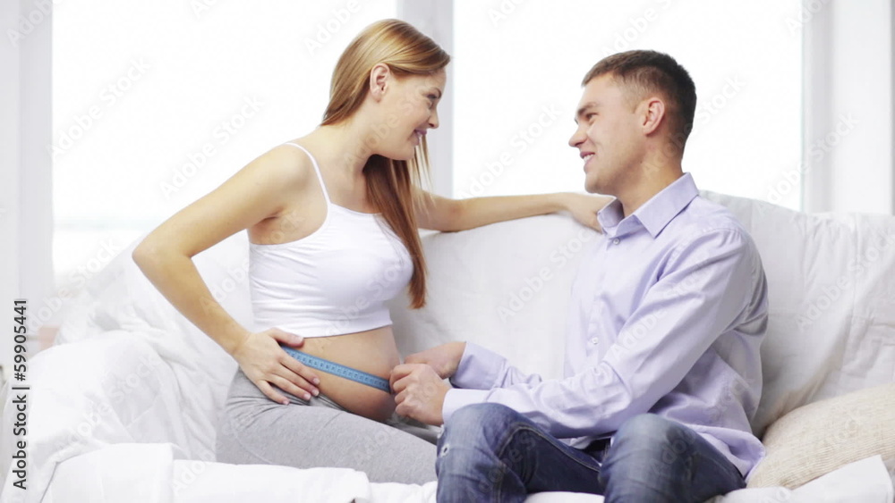 happy husband measuring waist of pregnant wife happy husband measuring waist of pregnant wife
