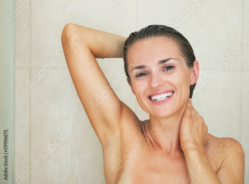 Smiling young woman washing in shower