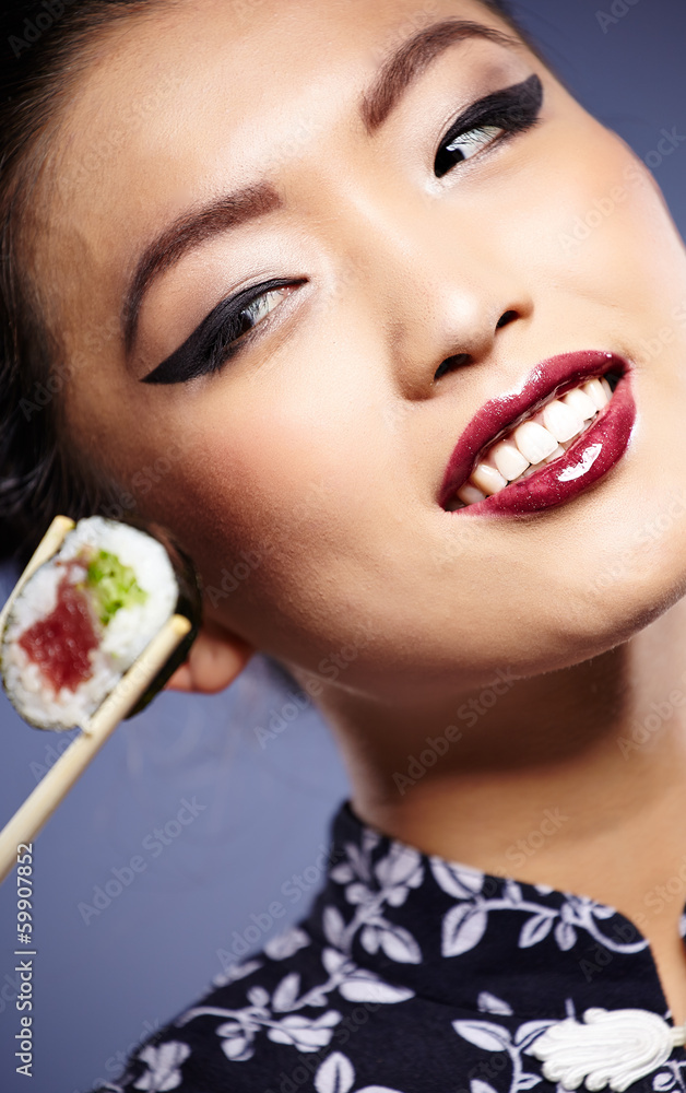 Sushi woman holding sushi with chopsticks looking at the camera Sushi woman holding sushi with chopsticks looking at the camera