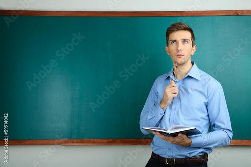 Young teacher near chalkboa...
