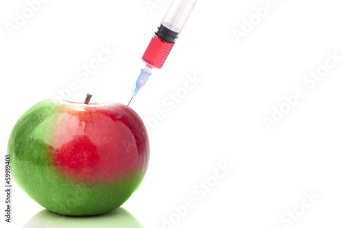 Apple in two colors with a syringe. Concept for GMO. photo