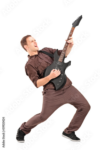 Full length portrait of a young man playing on electric guitar