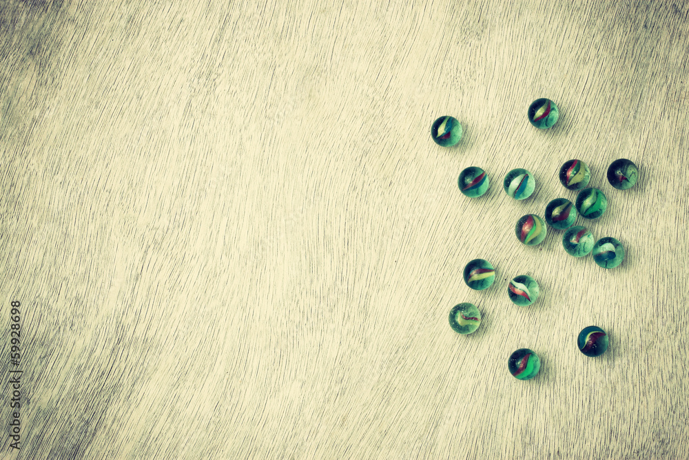 top view of collection of shiny marbles on wooden background.