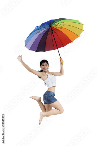 Woman jumping with rainbow umbrella