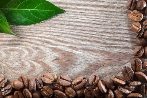 Coffee on wooden background with green leaves