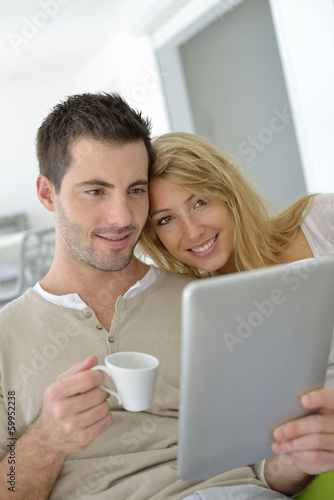 Cheerful couple using digital tablet at home