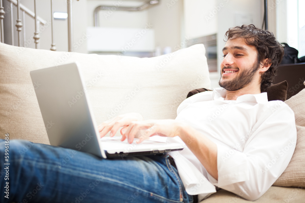 Man using a laptop in his apartment Man using a laptop in his apartment