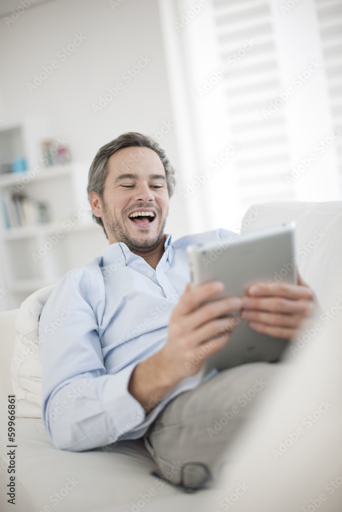 Attractive man at home using digital table Attractive man at home using digital table