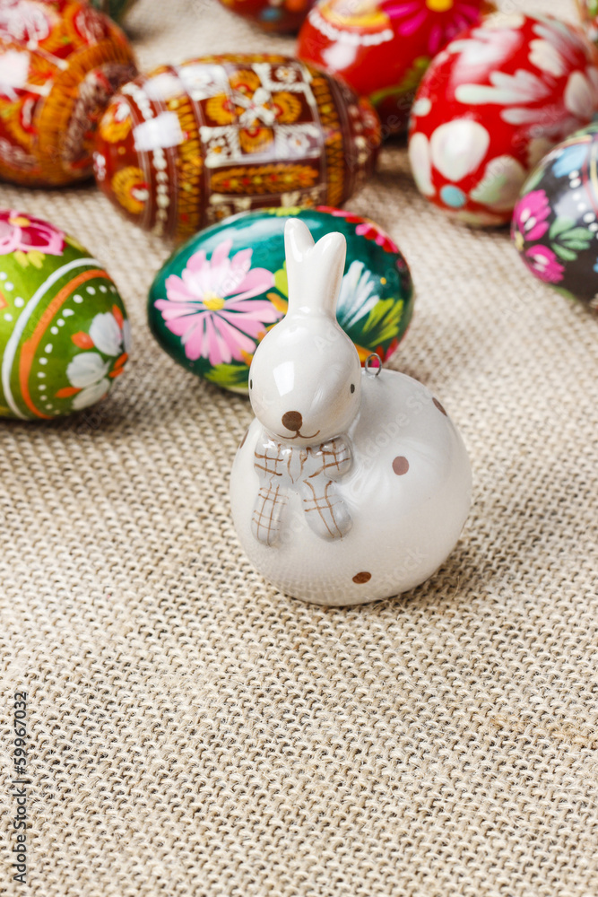 Obraz premium Easter eggs and ceramic rabbit on jute background