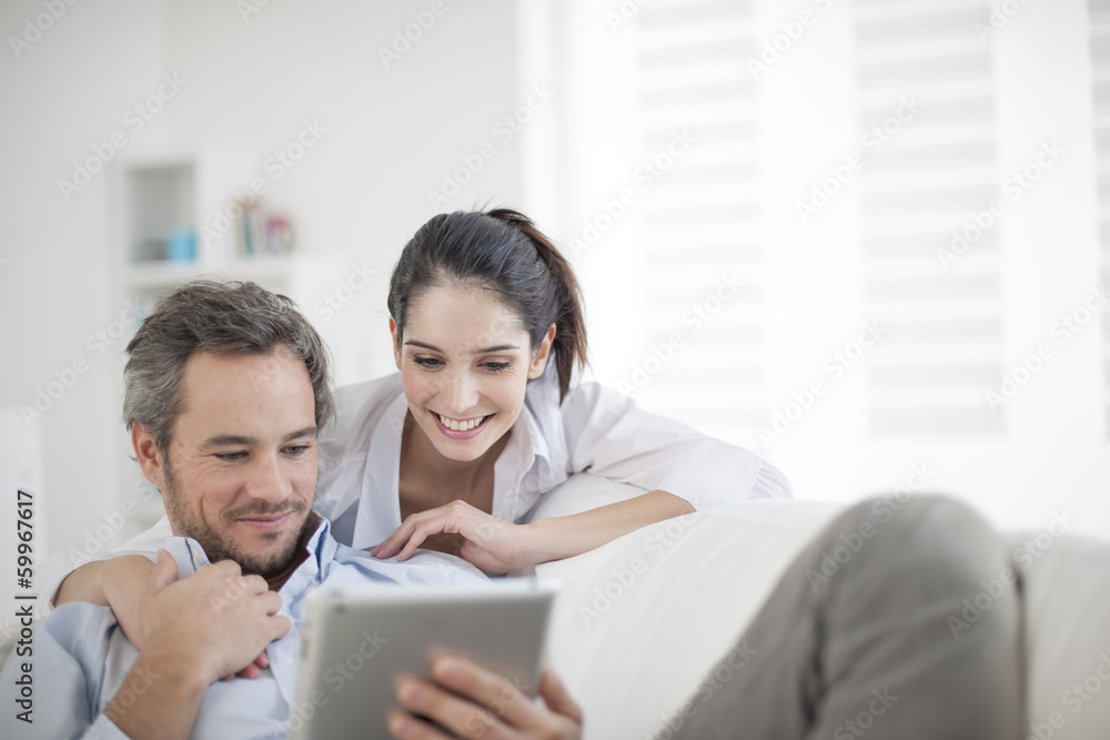 Cheerful couple using digital tablet at home Cheerful couple using digital tablet at home