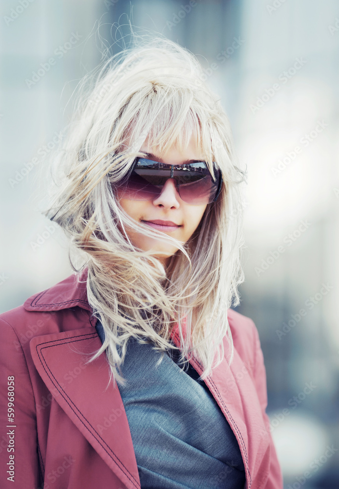 Blond woman in red jacket walking on the city street Blond woman in red jacket walking on the city street