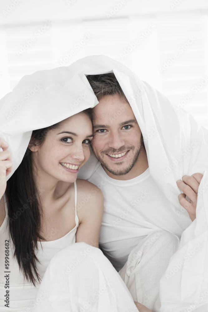 cheerful young couple wrapped in their quilt cheerful young couple wrapped in their quilt