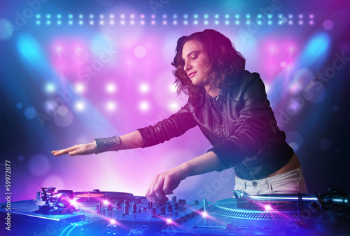 Disc jockey mixing music on turntables on stage with lights and