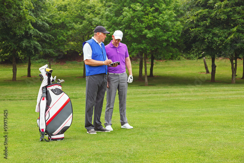 Fotografía Golfer and caddy looking at a course guide