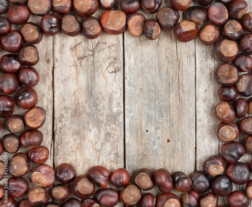 Frame with chestnuts on wooden desk