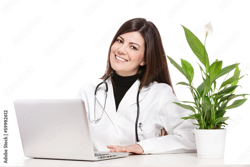 Female doctor sitting at her desk and smiles towards the camera