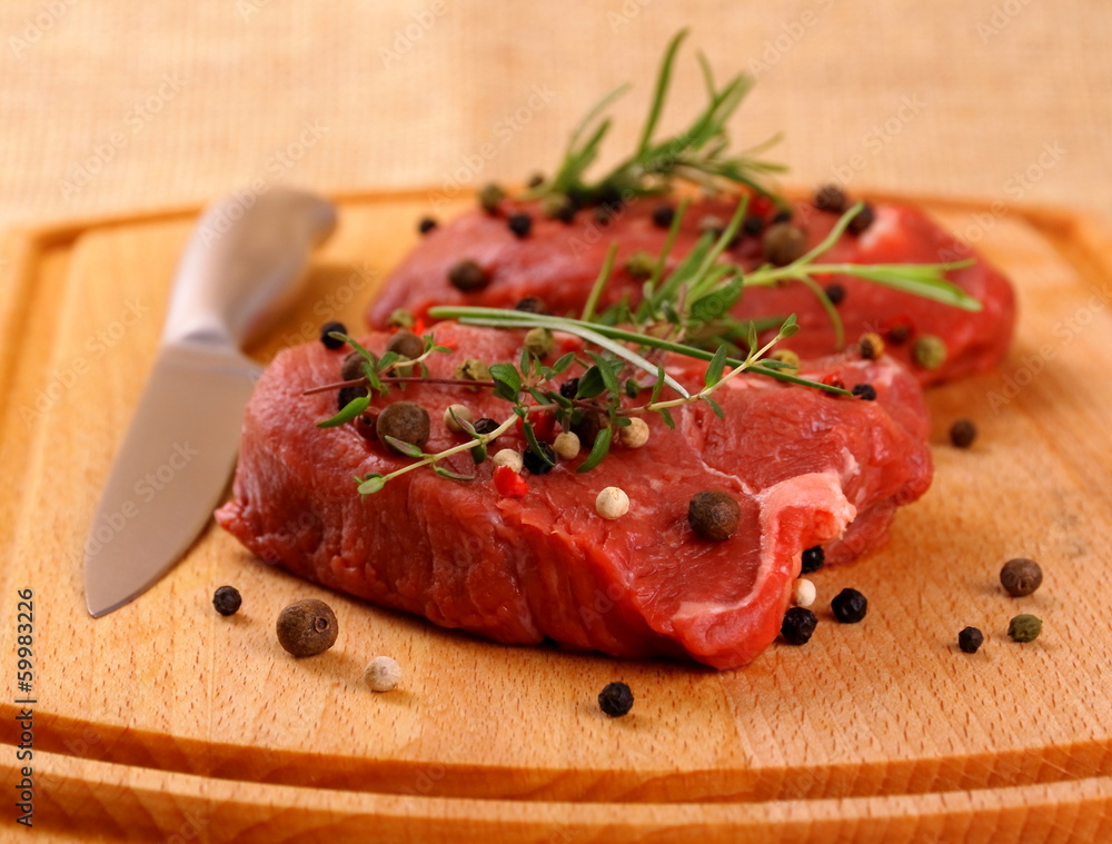 Two juicy beef steak with spices and steel knife Two juicy beef steak with spices and steel knife