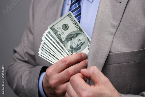 Fotografie Businessman putting money in pocket
