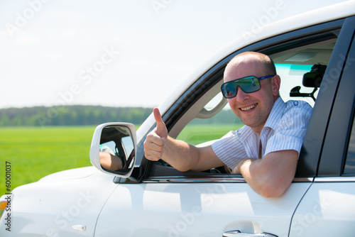 Happy adult man in white new car with thumbs up