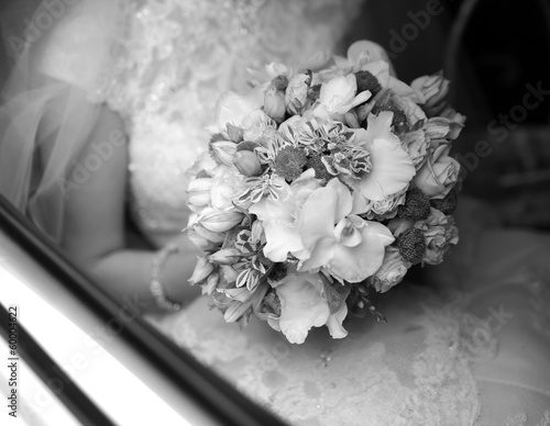 Bride on wedding day in car with bouquet
