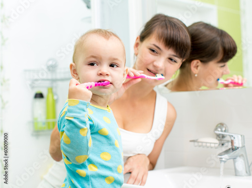 kid and mother brushing teeth