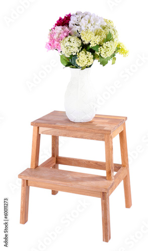 Vase with flowers on small wooden ladder, isolated on white