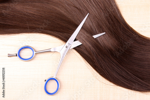 Long brown hair and scissors on wooden background