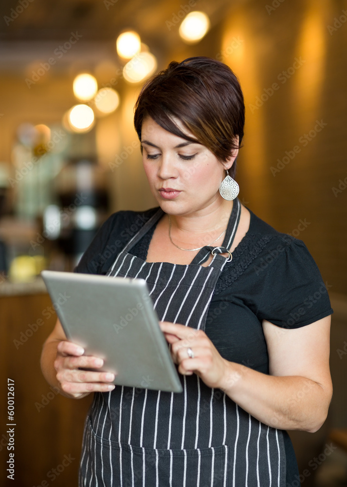 Owner Using Digital Tablet In Cafe Owner Using Digital Tablet In Cafe