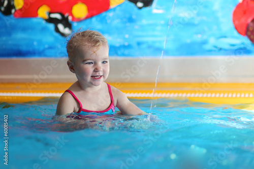 Adorable happy baby or toddler girl having fun in swimming pool