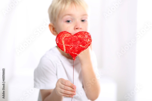 Mały kaukaski chłopiec pokazuje czerwone walentynkowe serduszko