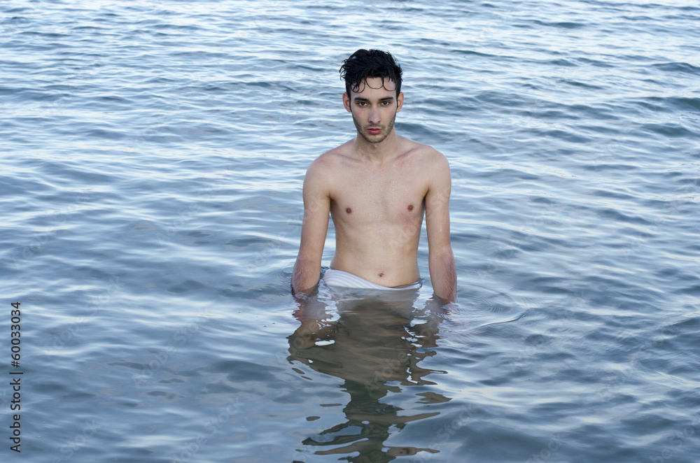 Beautiful man in swimsuit relaxing in sea during summer vacation Beautiful man in swimsuit relaxing in sea during summer vacation