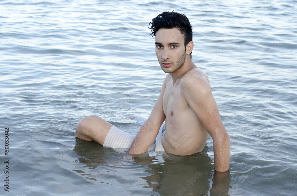 Beautiful man in swimsuit relaxing in sea during summer vacation